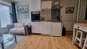 Una cocina compacta con armarios blancos, horno integrado y campana extractora de acero inoxidable.