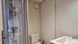 Un baño moderno con cabina de ducha de vidrio, inodoro y lavamanos blanco.