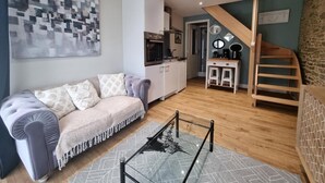 Una sala de estar moderna con un sofá, una mesa de centro y una cocina al fondo.