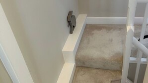 A carpeted staircase with white railings and a small shelf against the wall.