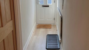 A hallway with a wooden door, a white door with frosted glass panels, a doormat, and a radiator on the wall.
