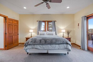 A bedroom with a large bed, two bedside tables with lamps, a ceiling fan, a window with curtains, and a view of the outdoors. - Bryce Canyon Hilltop Lodge • Spa, Views & High-End Comfort (Hatch)