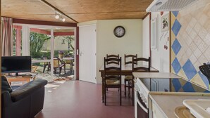 A cozy living room with a TV, a sofa, and a dining area with chairs and a table. - Chalet La Brousse No. 2 – sleeps 5 – with pool (Salignac-Eyvigues)