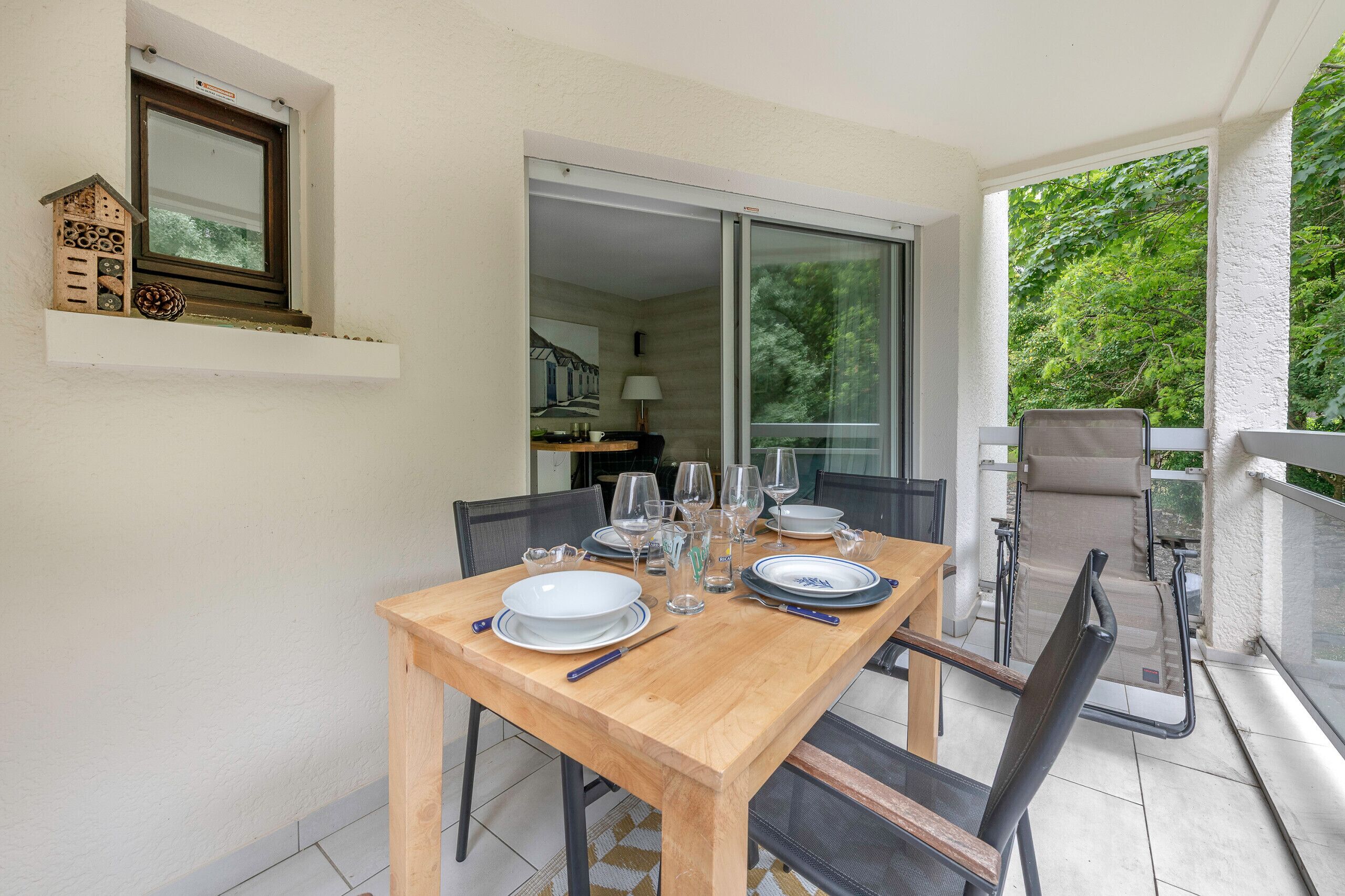 A dining area with a wooden table set for four, chairs, and a glass balustrade.