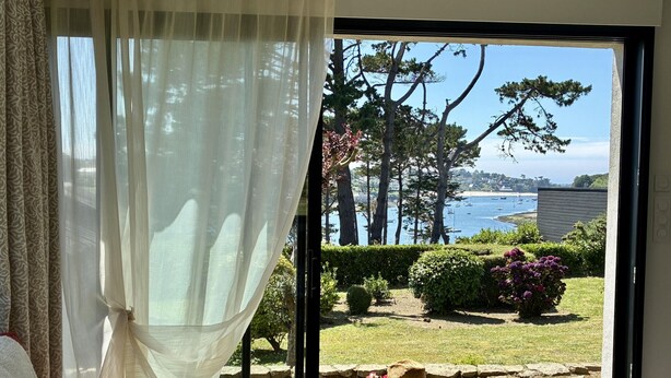 A room with a large window overlooking a garden and a coastal view. - View over the Aber - House for 8 - Large garden (Lannilis)