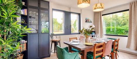 A modern kitchen with a dining area, featuring a large window, wooden cabinets, and a variety of chairs.