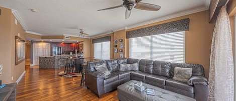 A spacious living room with a large sectional sofa, a ceiling fan, and hardwood flooring.