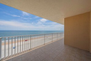 A balcony with a view of the beach and ocean.