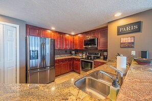 A modern kitchen with stainless steel appliances, granite countertops, and wooden cabinets.