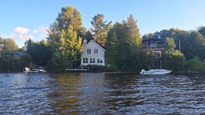 Une maison au bord d’un lac, avec un quai et un bateau.