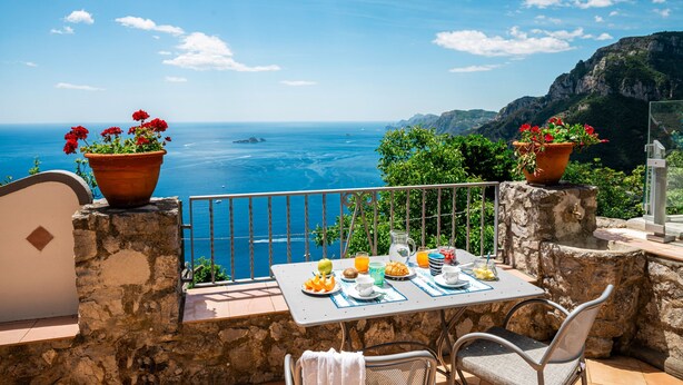 Mesa servida con alimentos para el desayuno con vistas a un paisaje costero.