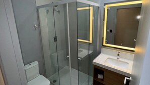 A modern bathroom with a glass-enclosed shower, a toilet, and a vanity with a mirror. - POUSADA BIG BEAR 2 (Campos do Jordao)