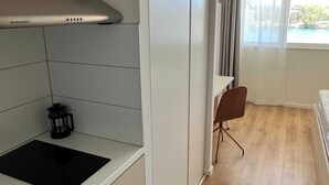 Eine kleine Küche mit Einbauherd, Kaffeemaschine und einem fenster mit Vorhängen.