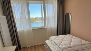Ein Hotelzimmer mit Bett, Schreibtisch und Blick auf ein Gewässer durch ein Fenster.