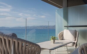 Un balcon doté d’une balustrade en verre, d’une table, de deux chaises et d’une plante en pot.