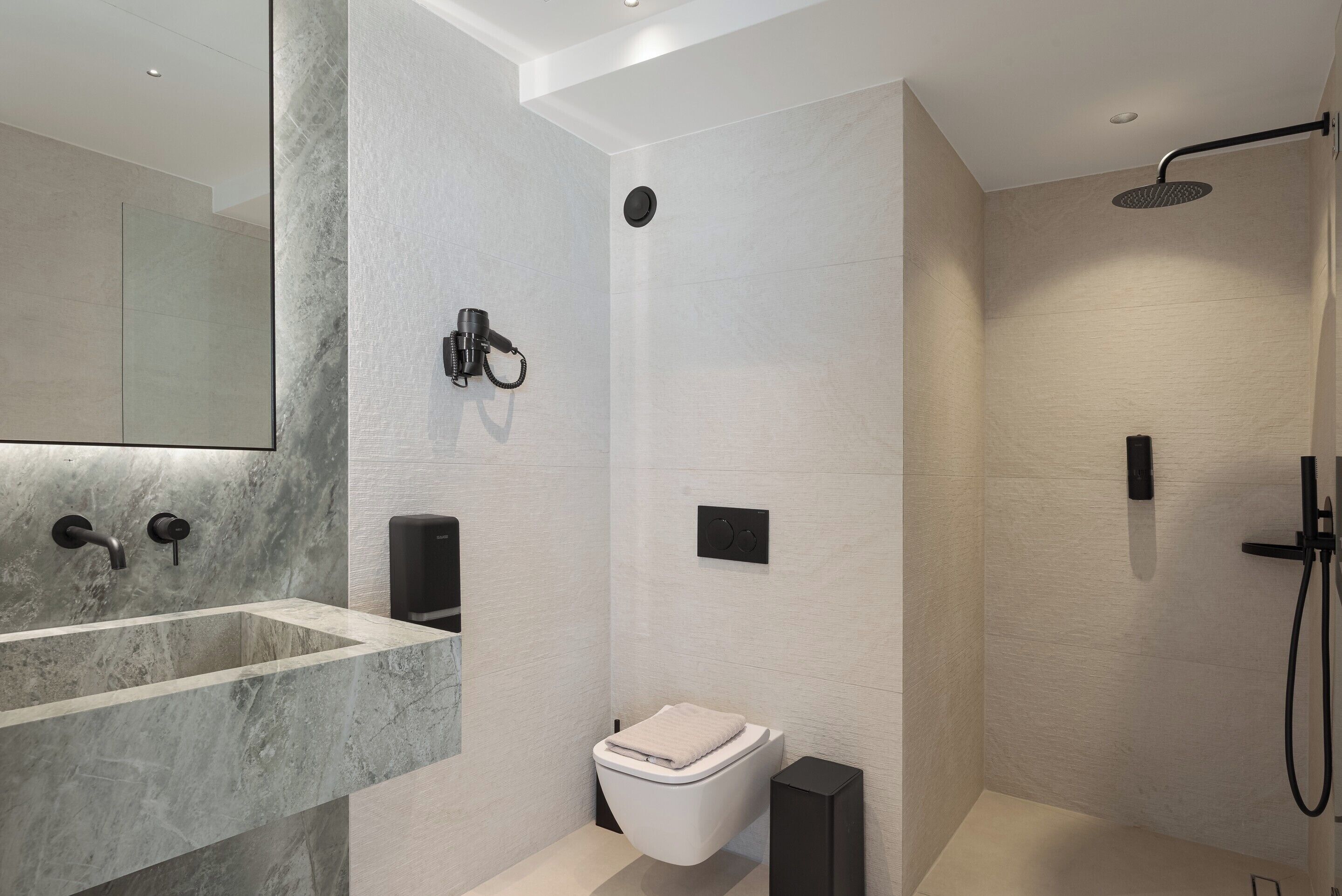 Une salle de bain moderne avec un lavabo en marbre, des toilettes et une douche.