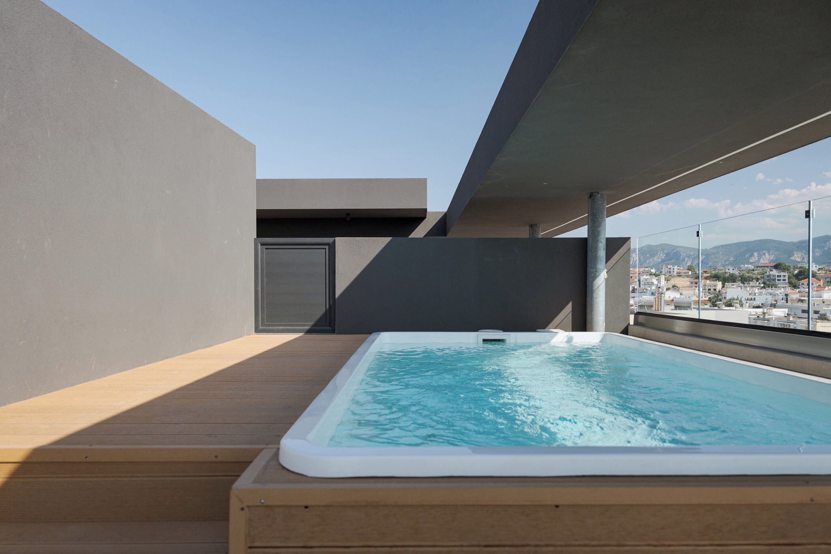Une piscine sur le toit, dotée d’une terrasse en bois, offrant une vue sur la ville et présentant un design architectural moderne.
