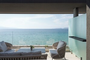 Een balkon met uitzicht op zee, rieten meubels en een flatscreen-tv.