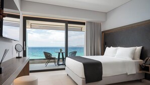 Habitación de hotel moderna con una cama grande, un escritorio y vista al mar.