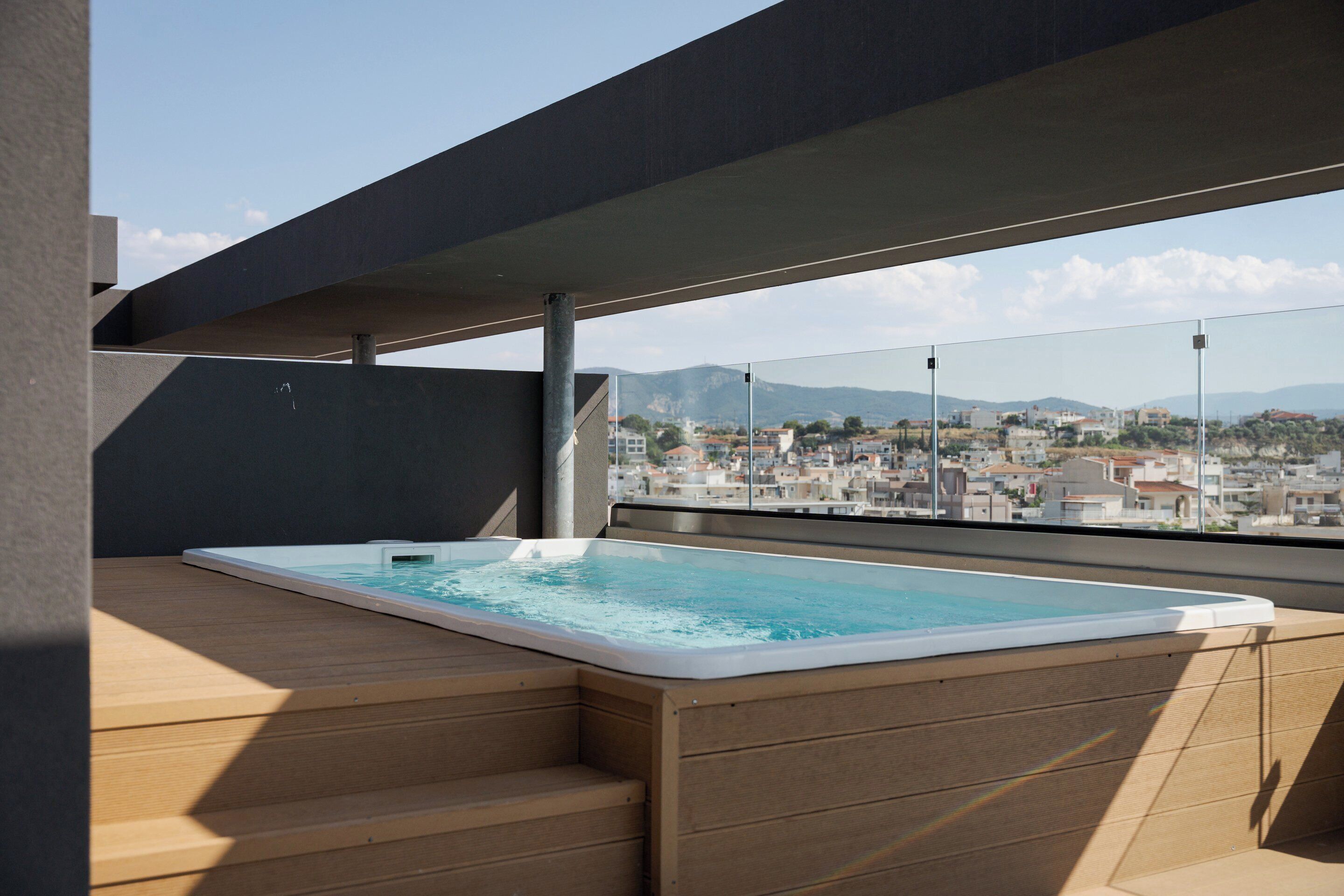 Ein Pool auf dem Dach mit Holzstufen und Blick auf die Stadt.