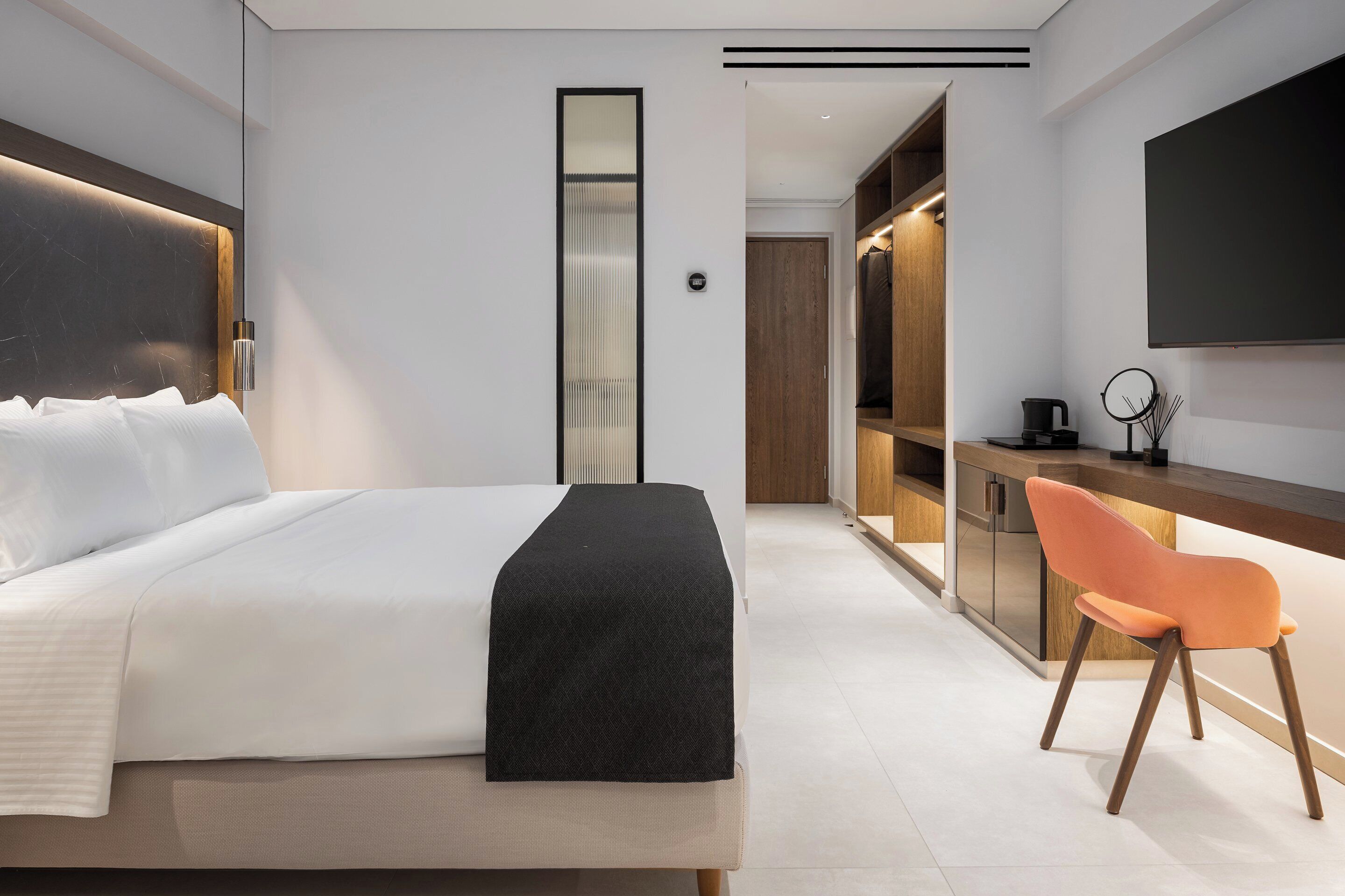 A modern hotel room with a large bed, a desk, and a chair.