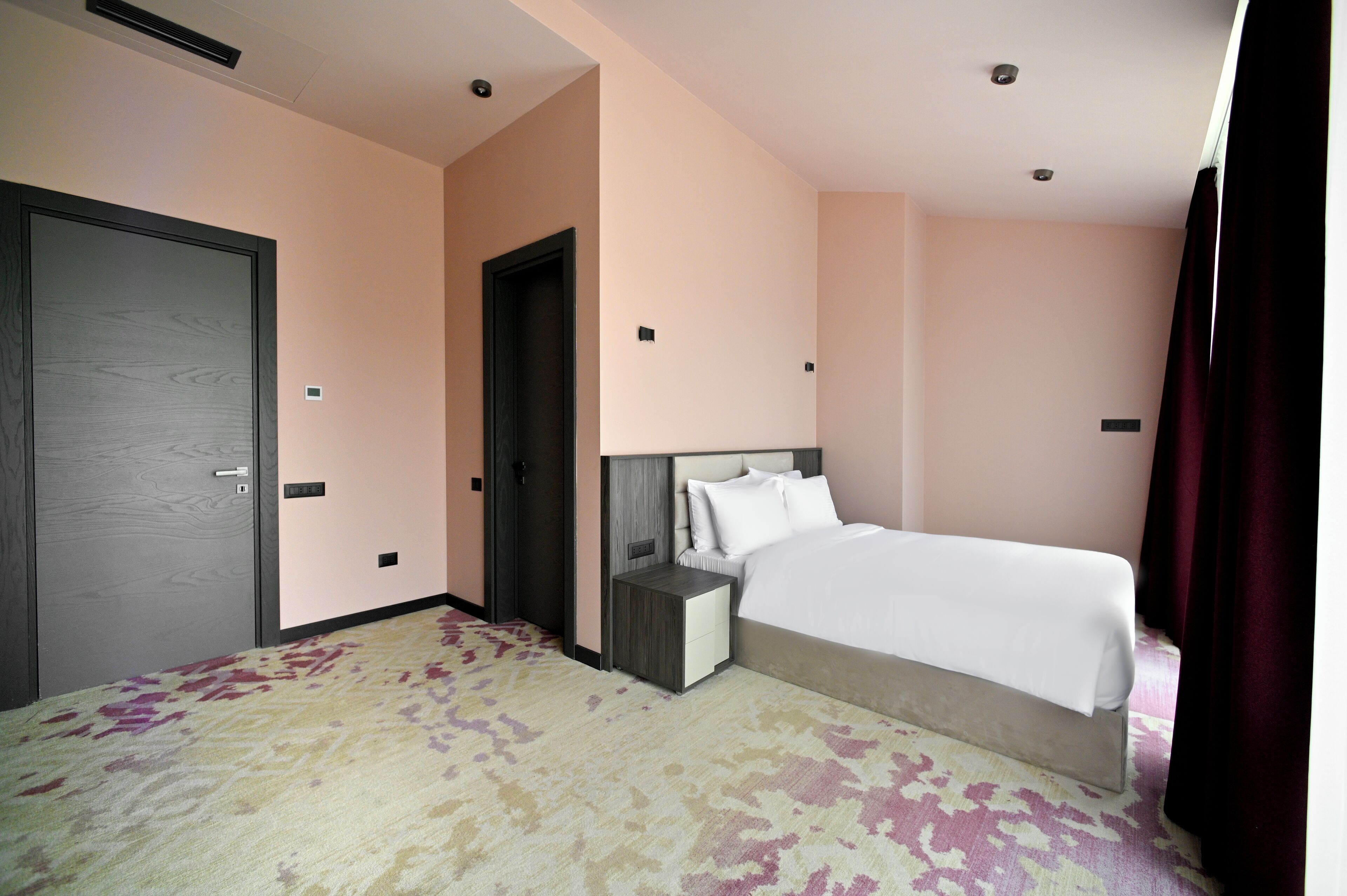 Habitació d'hotel amb llit, taulell de nit i una porta.