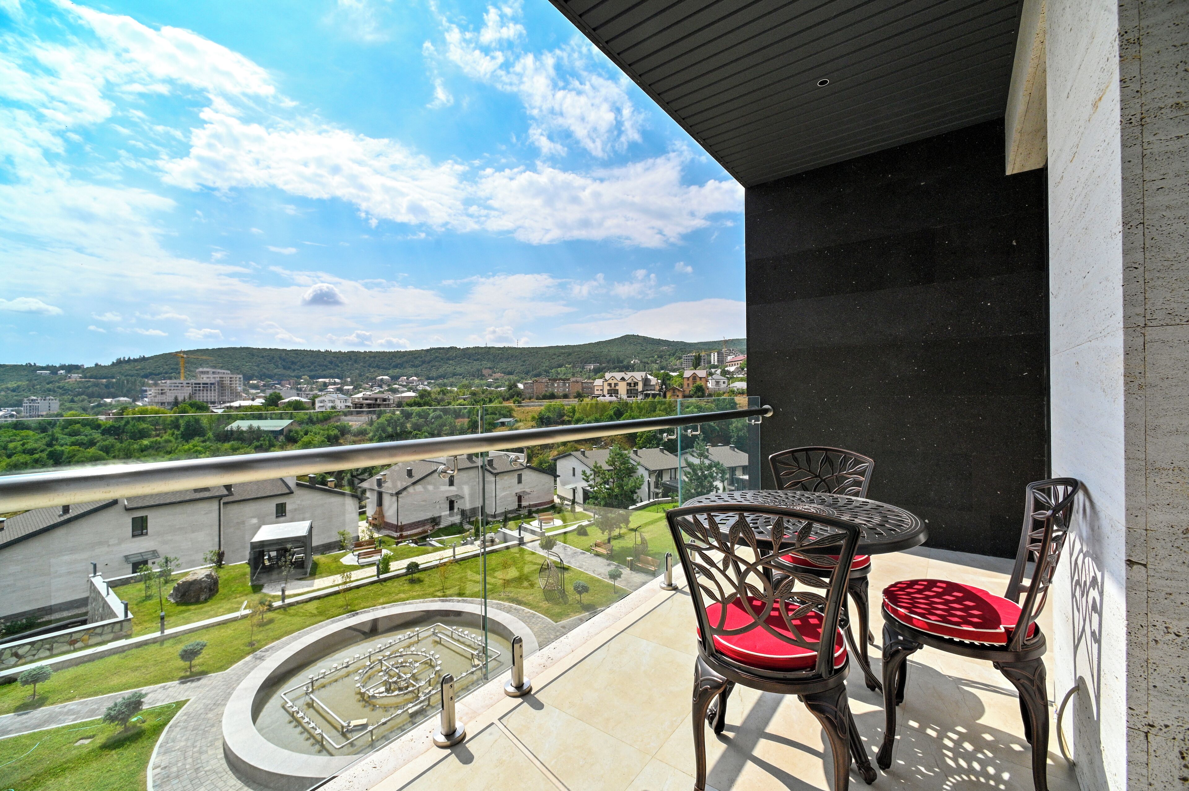 A balcony with a view of a cityscape, including buildings and a park.