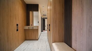 A modern hallway with wooden walls, a bench, and a central counter with a mirror.