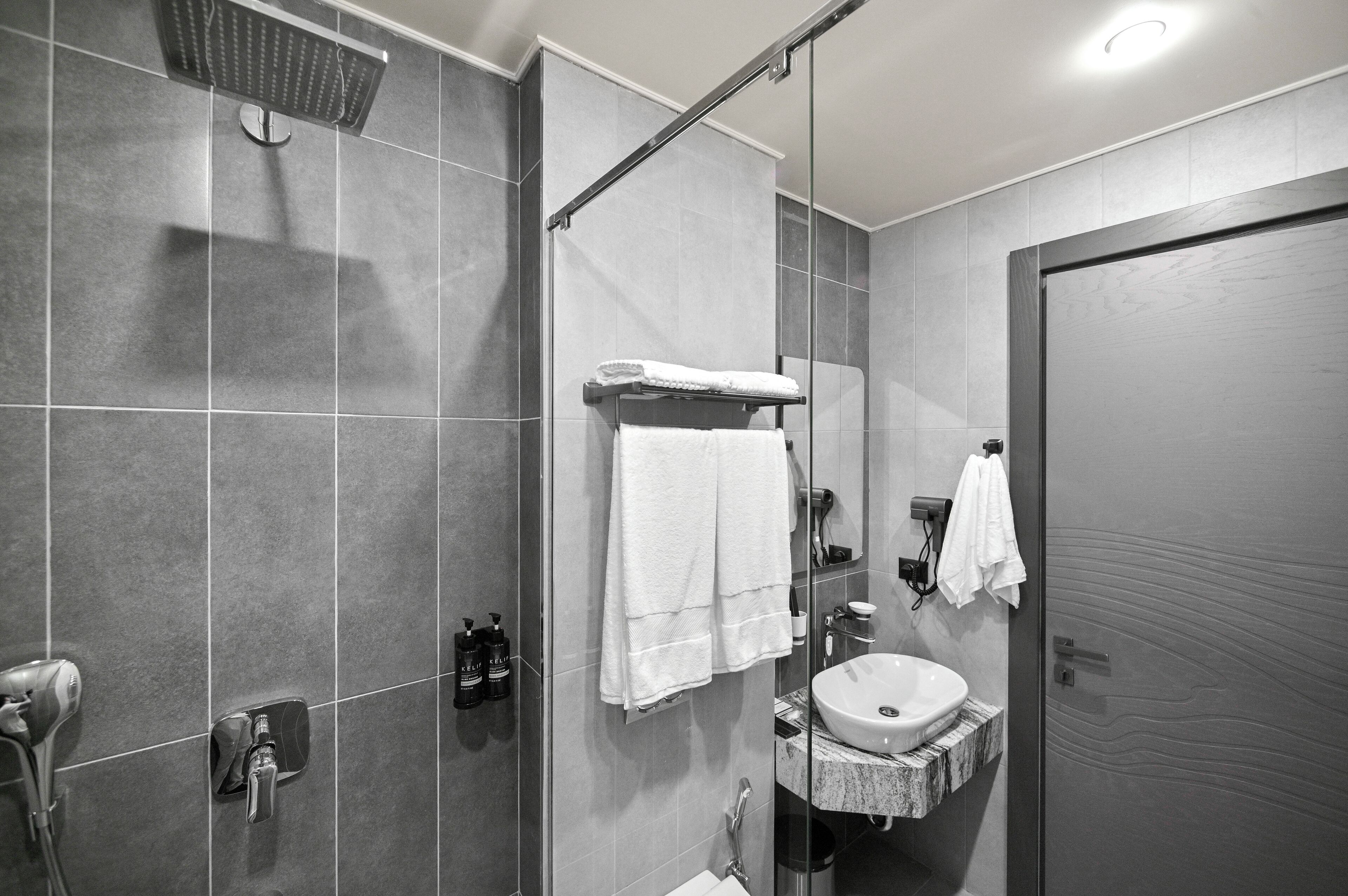 A modern bathroom with a glass-enclosed shower, a vanity with a sink, and a towel rack.