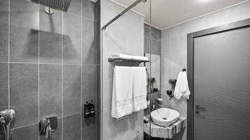 A modern bathroom with a glass-enclosed shower, a vanity with a sink, and a towel rack.