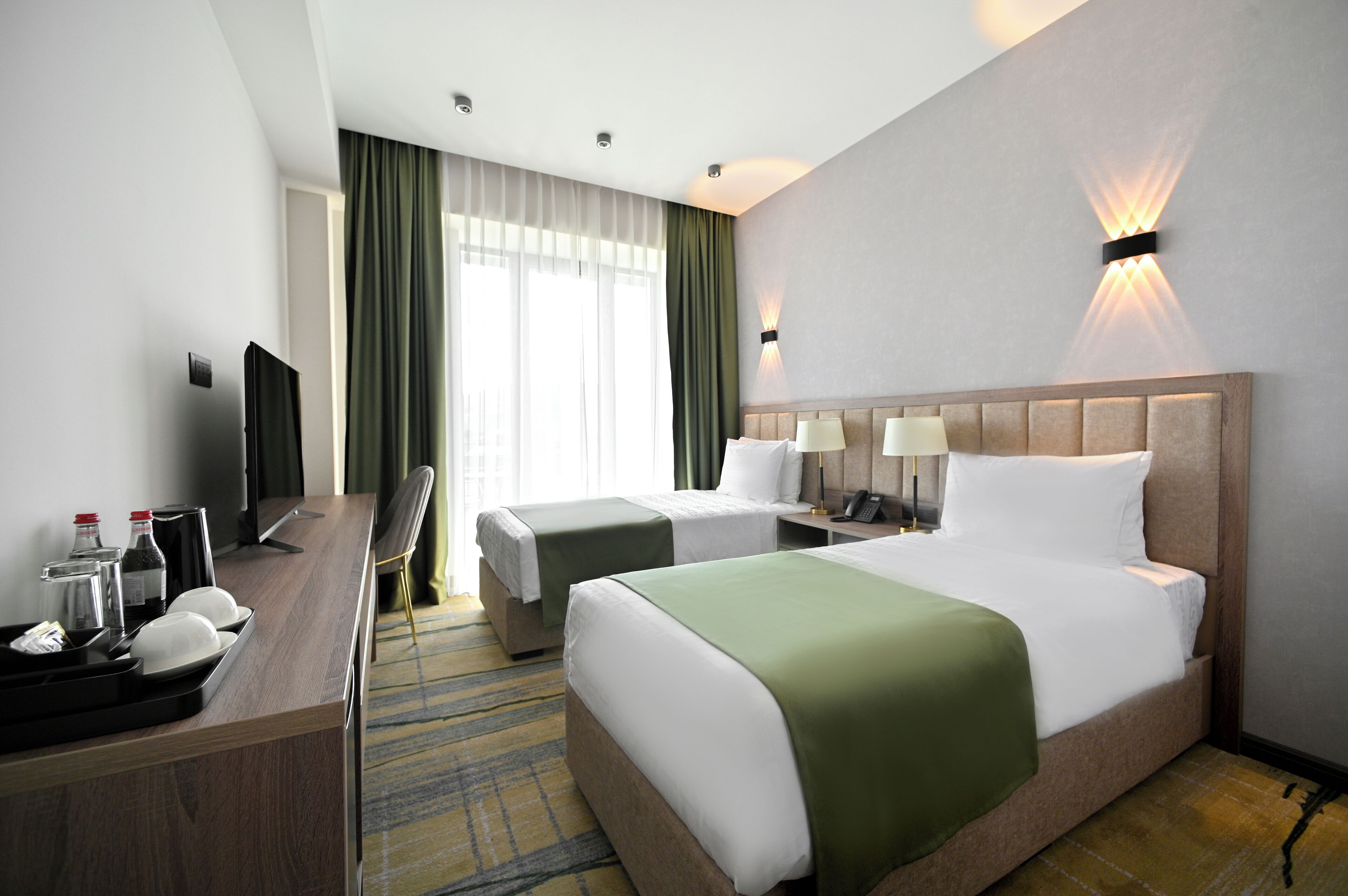 Une chambre d’hôtel avec deux lits, un bureau avec une télévision et un minibar.