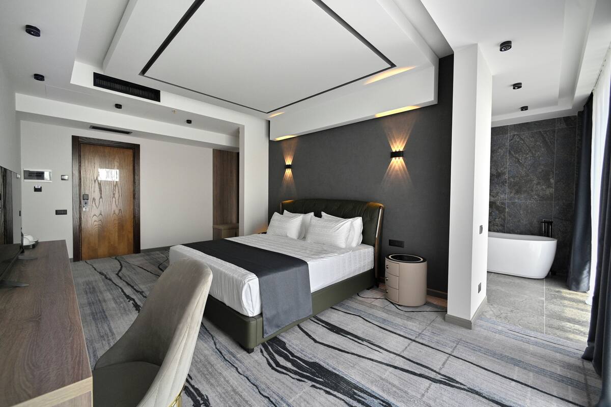 Una habitación de hotel moderna con una cama grande, un escritorio y un baño.