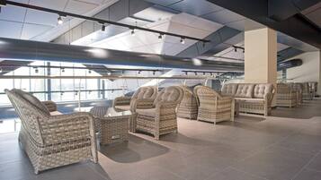 A modern lounge area with wicker furniture and a high ceiling with skylights.