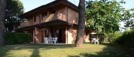 Una casa de dos pisos con balcón, césped y árboles.