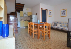 A compact living space with a dining area, kitchenette, and a sofa.