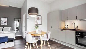 A modern kitchen with grey cabinets, a round wooden table, and a pendant light. - Chic Ground-Floor Studio in Midtown (Aarhus)