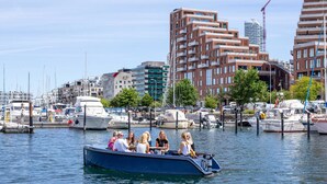 A boat with passengers docked at a marina with buildings in the background. - Chic Ground-Floor Studio in Midtown (Aarhus)