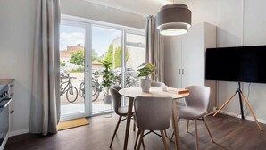 Een moderne kamer met een eettafel, stoelen, een televisie en uitzicht op fietsen buiten.