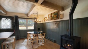 A cozy room with a wooden table and chairs, a fireplace, and a window with curtains. - Scenic Vail Escape | Walk to Shuttle, Near Trails | Newly Renovated (Vail)