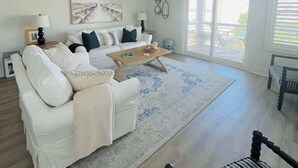 Un salón espacioso con un sofá blanco, una mesa de centro y un sillón a rayas.