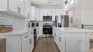 Una cocina moderna con armarios blancos, electrodomésticos de acero inoxidable y una isla central.