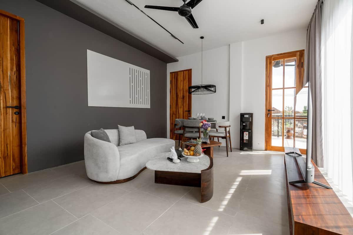 A modern living room with a grey sofa, a wooden coffee table, and a TV on a wooden stand.