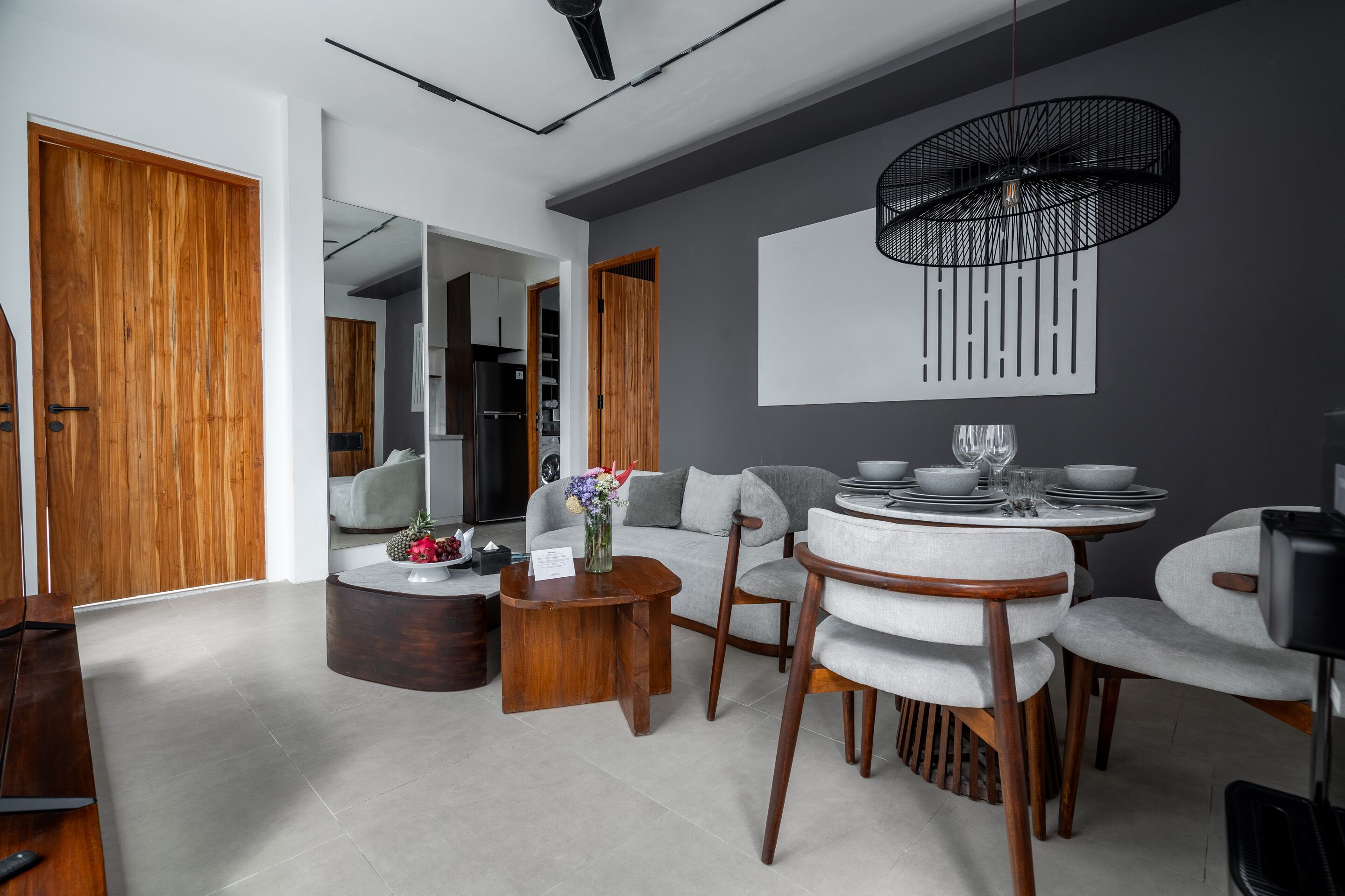A modern living room with a dining area, featuring a round table, chairs, and a large mirror.