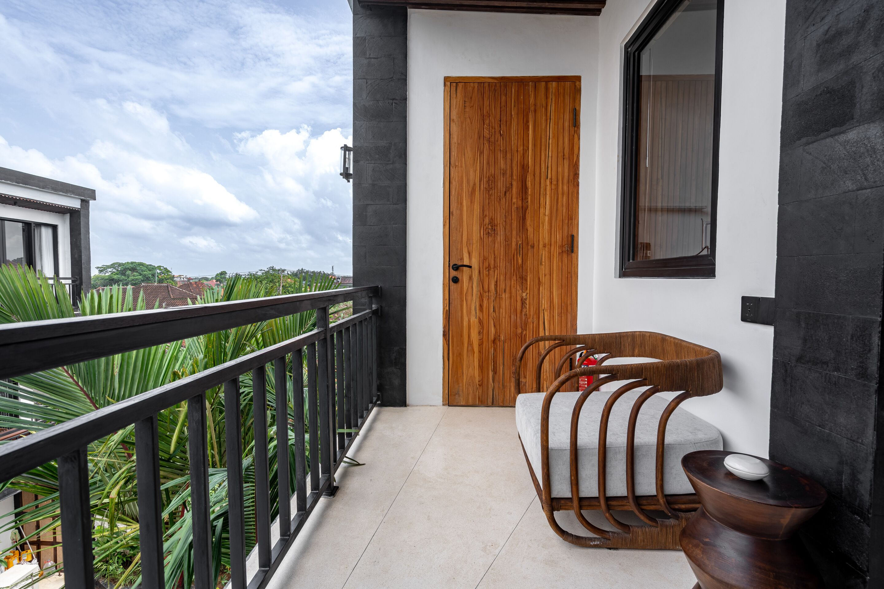 A balcony with a wooden door, a cushioned bench, and a small table.