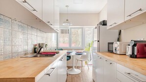 A modern kitchen with white cabinets, a wooden countertop, and a dining area with a white table and chairs.