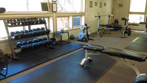 A gym with various exercise equipment, including dumbbells, a bench, and a weight machine.