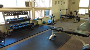 Un gimnasio con diversos equipos de ejercicio, como mancuernas, un banco y una máquina de pesas.