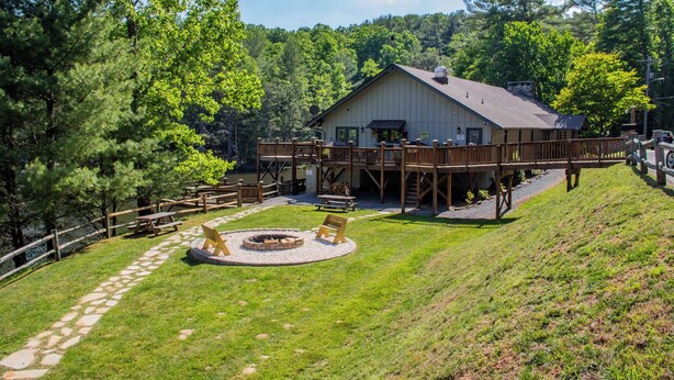 A lodge with a deck, a fire pit, and a pond.