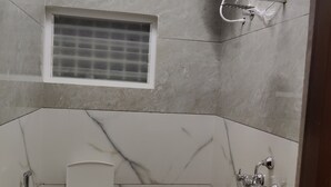 A bathroom with a toilet, a window, a water heater, and a bathtub. - Nandan Residency  (Mysore)