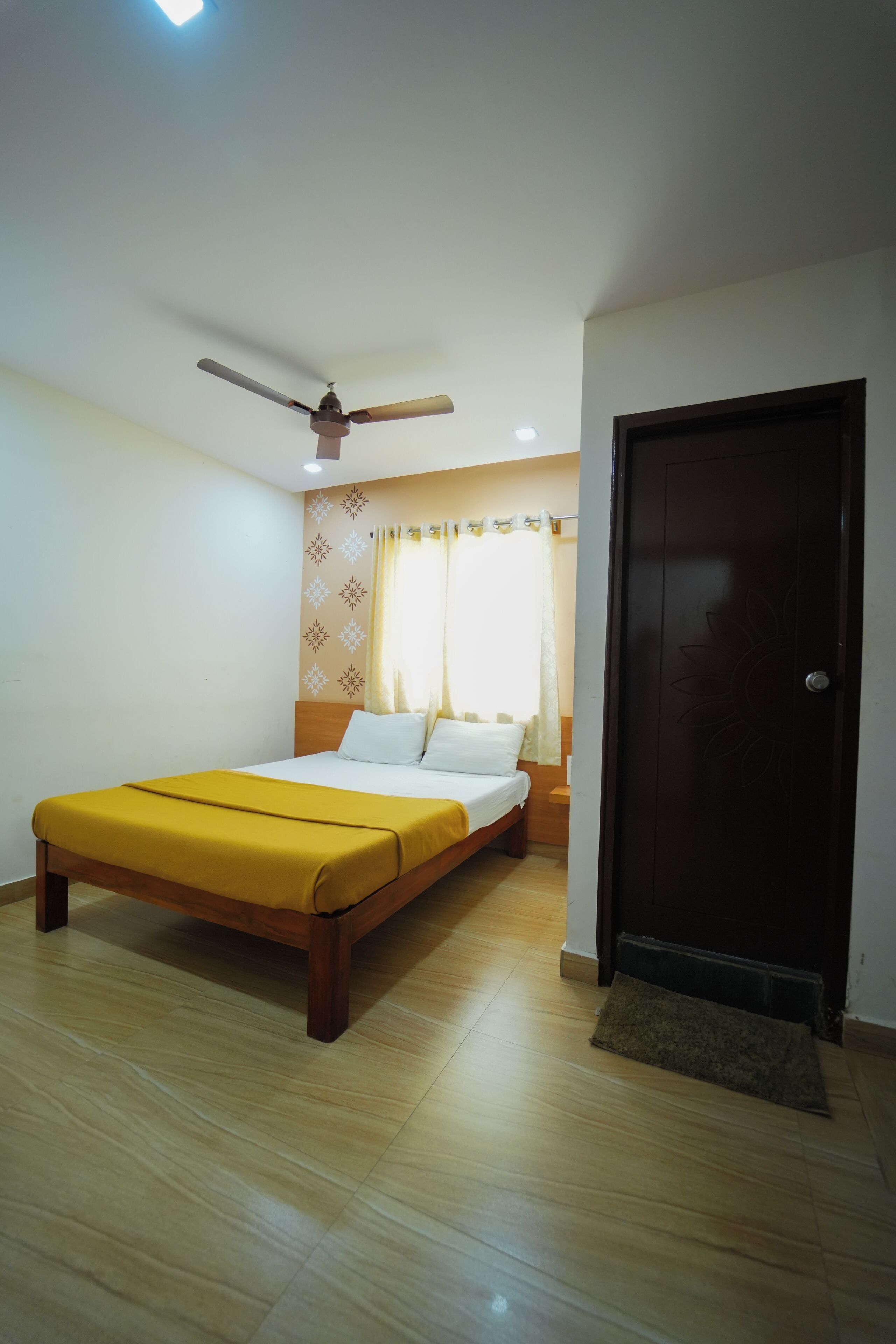 A bedroom with a bed, a ceiling fan, a door, and a window with curtains.